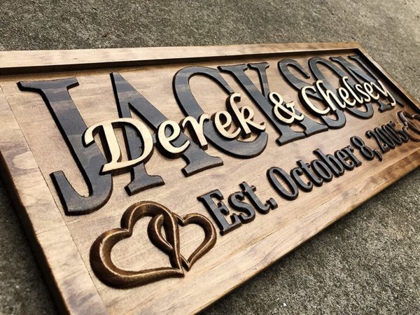 Carved wood family name sign with the couple's first names, two hearts and an established date